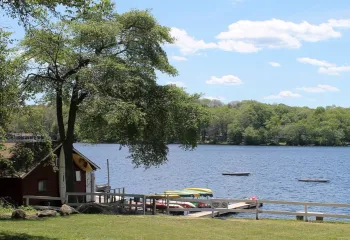 A waterfront view of Camp Westwood showcasing kayaks, paddle boards, and canoes.