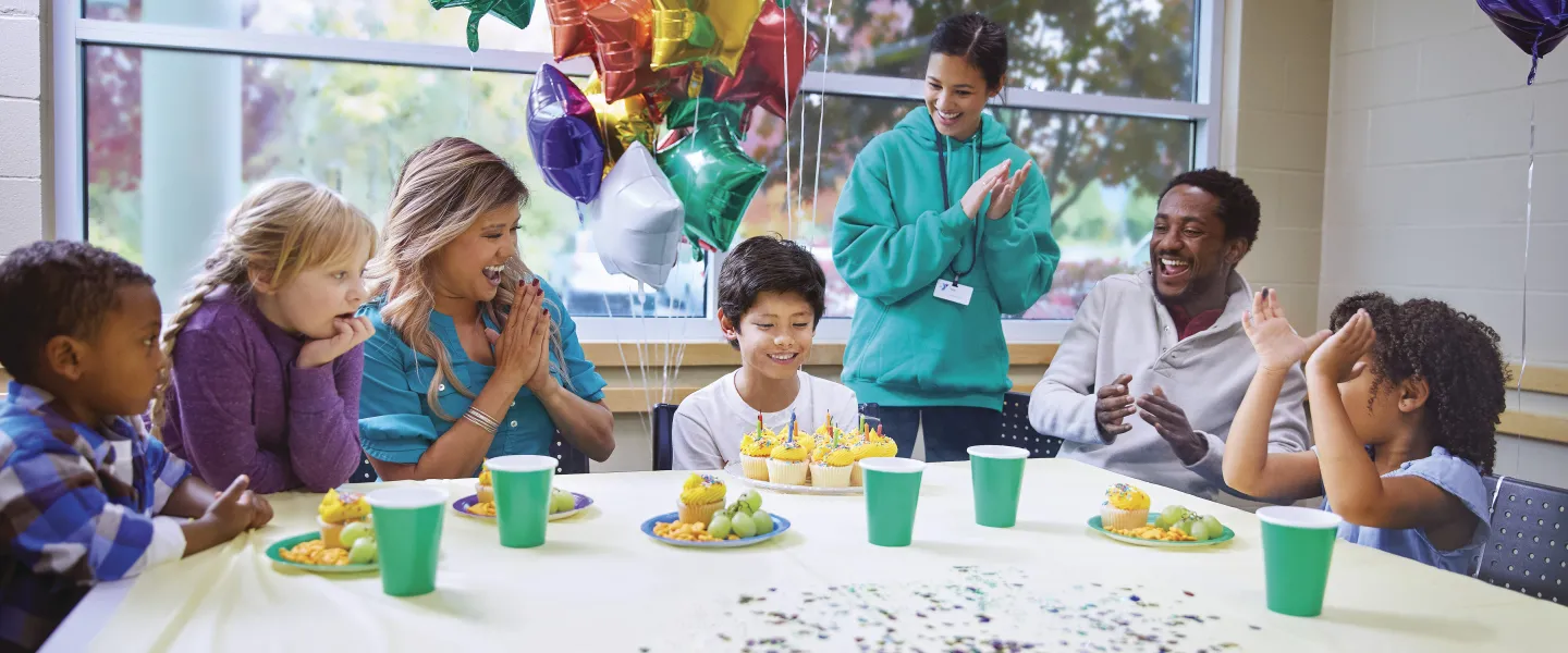 Kids sitting around a table celebrating a birthday