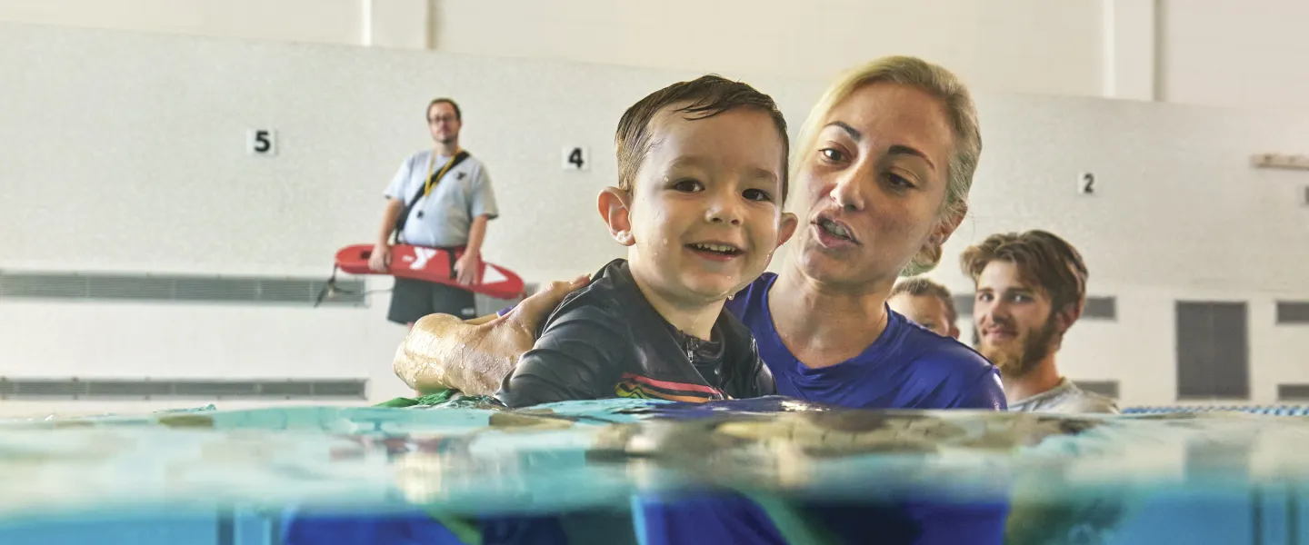 Female swim instructor teaching a young boy to siwm