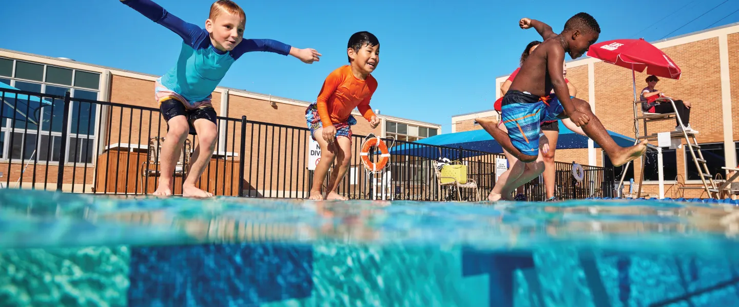 Kids jumping into an outdoor pool