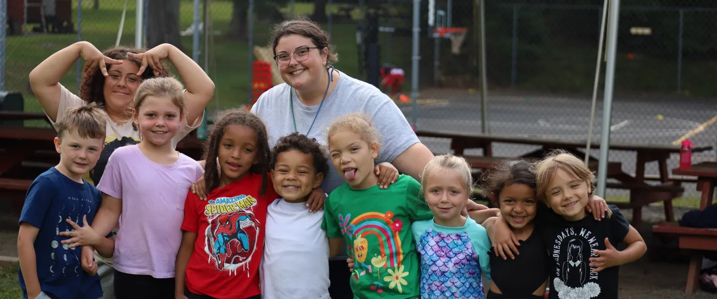 Female counselor standing with 9 campers