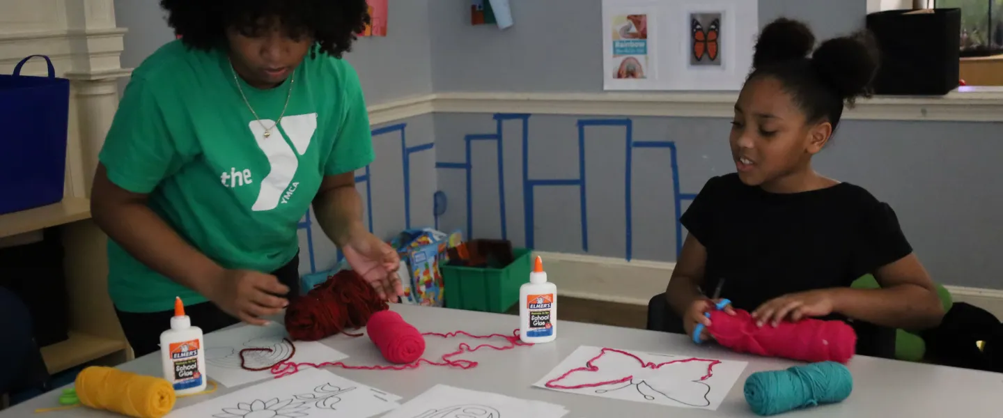 Female staff assisting a girl with her art project