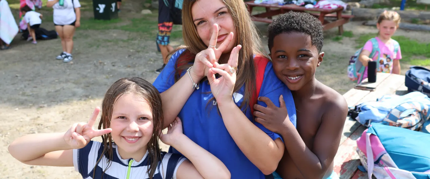 Camp Counselor smiling with campers kids on the beach at the lake