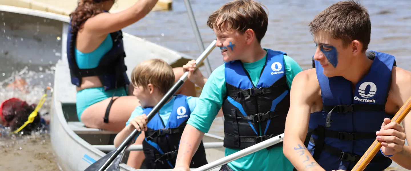 Boys Smiling in a canoe at summer camp on a lake
