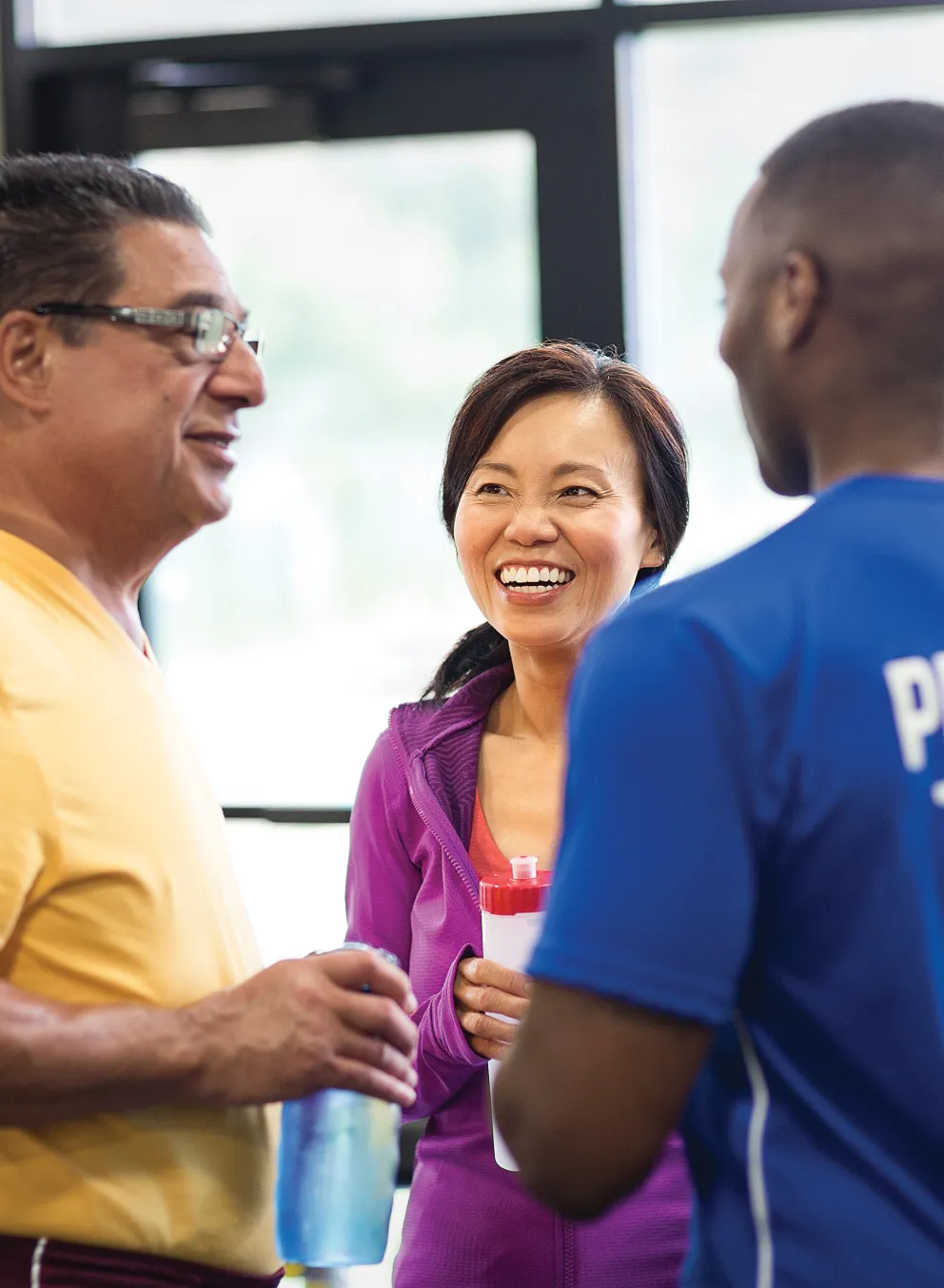 Male personal trainer talking with a man and a woman