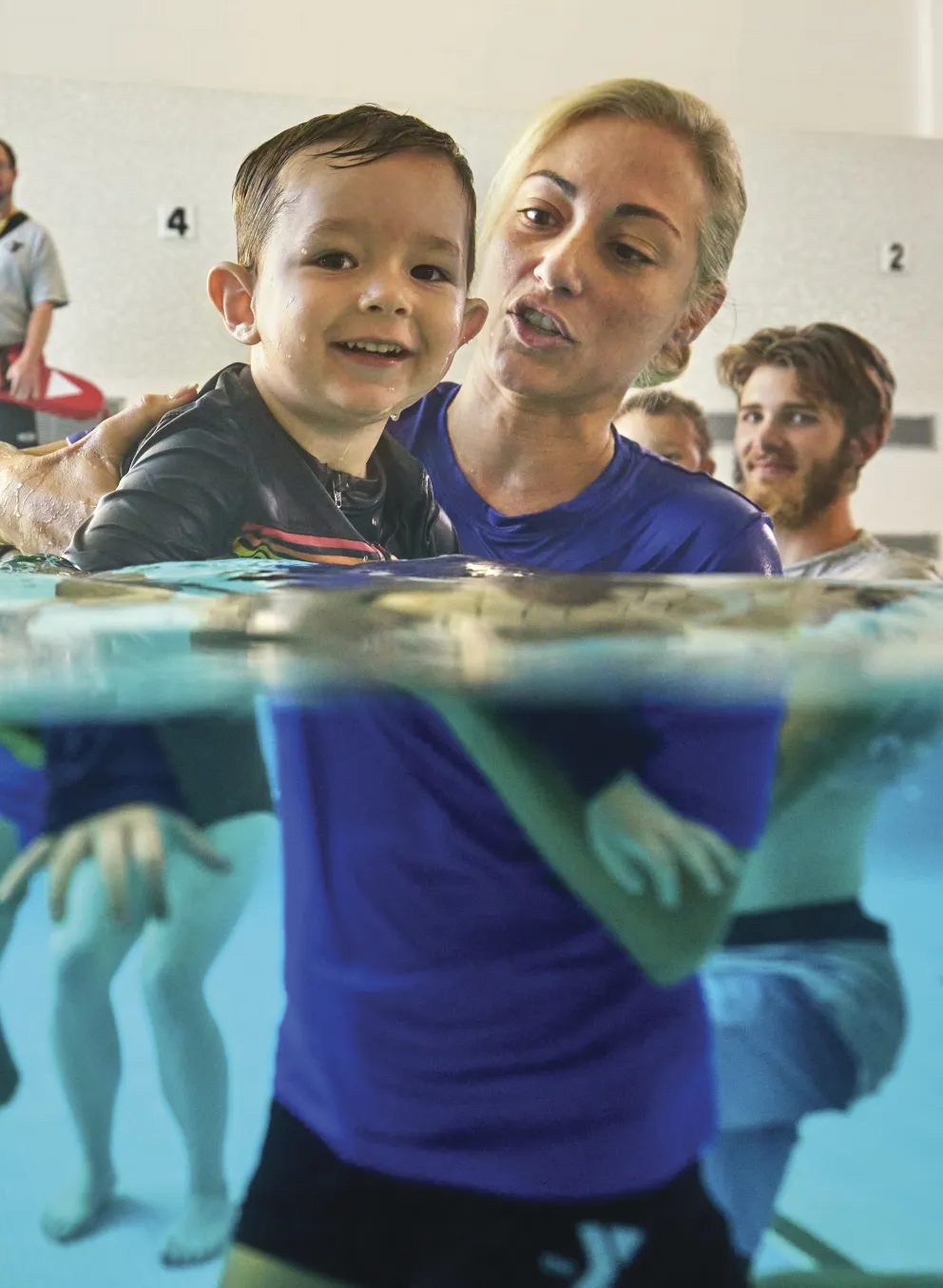 Female swim instructor teaching a young boy to siwm