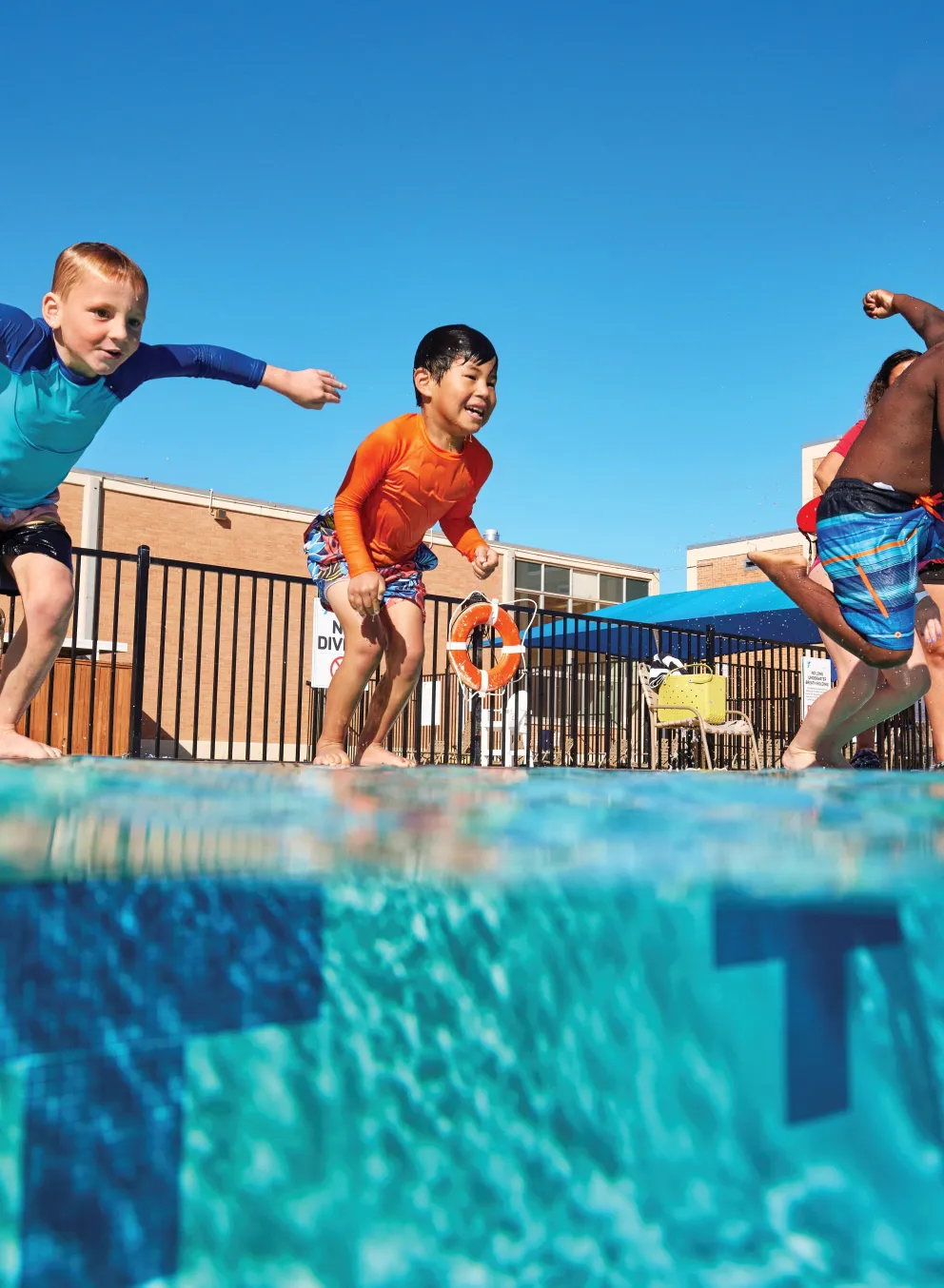 Kids jumping into an outdoor pool