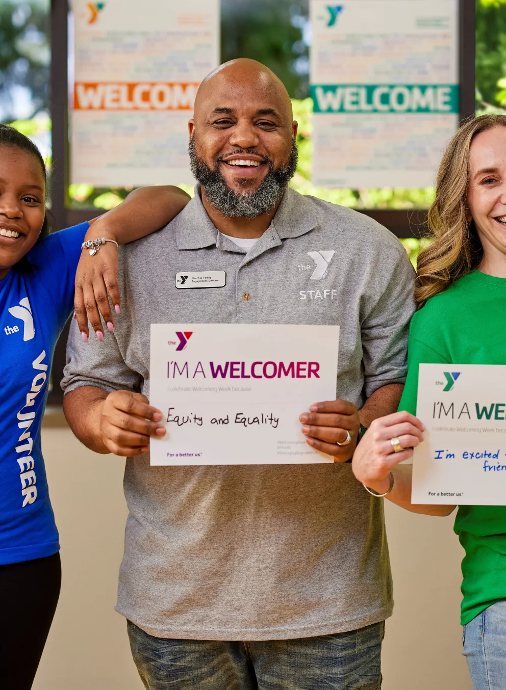 2 female and 1 male staff holding "I'm a welcomer" signs
