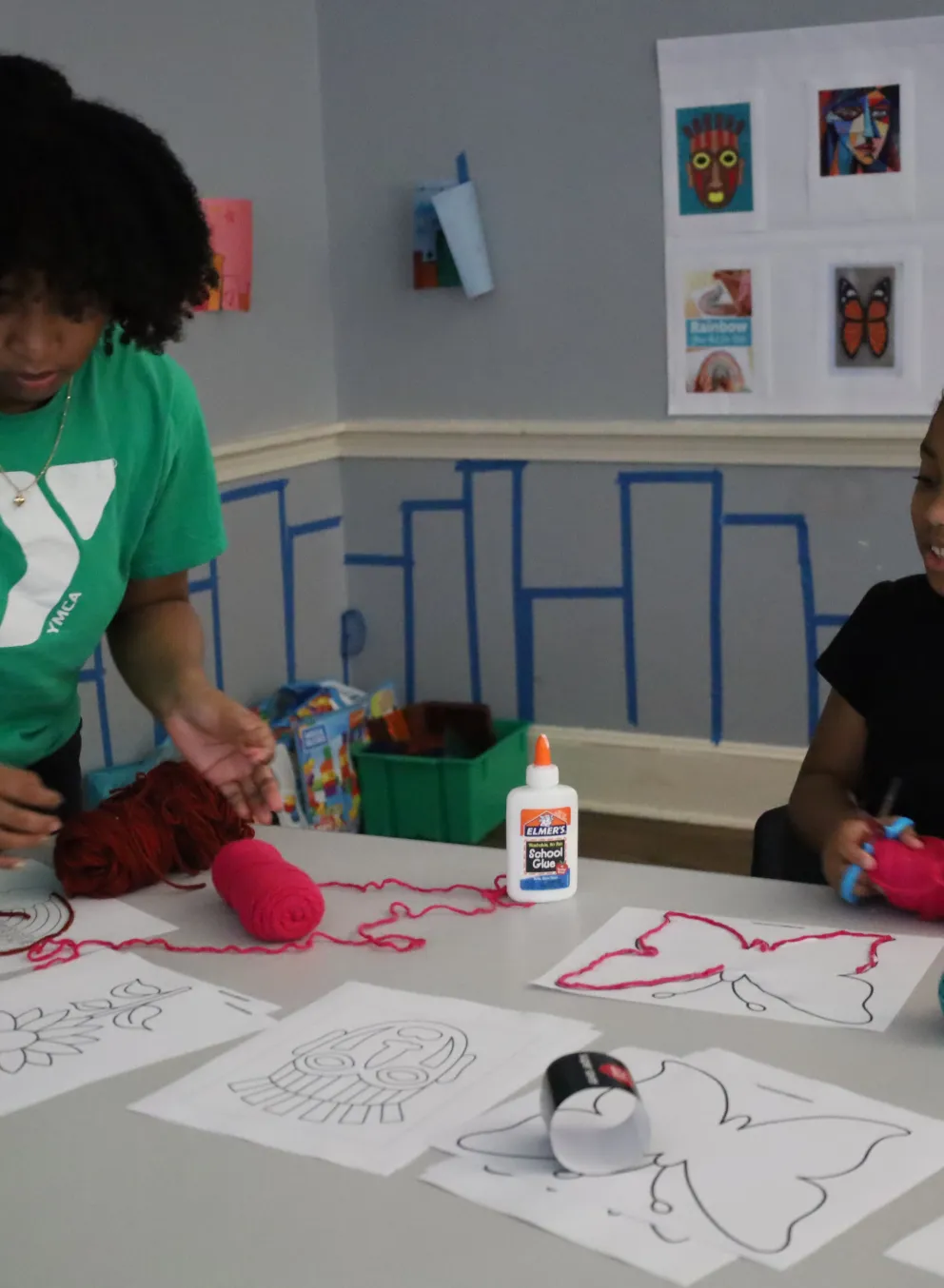 Female staff assisting a girl with her art project