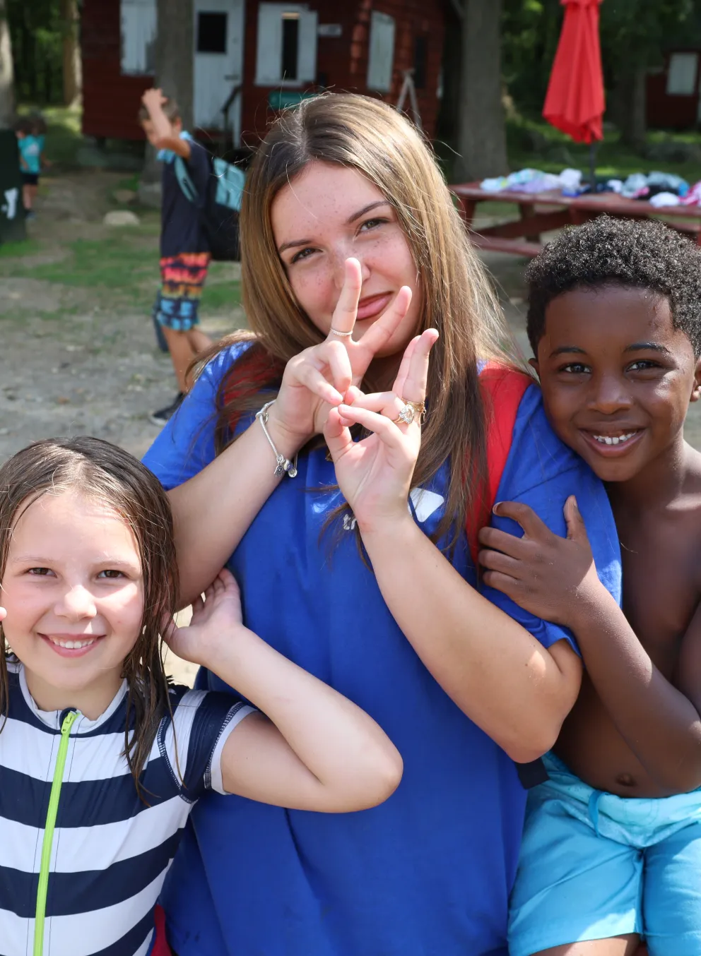 Camp Counselor smiling with campers kids on the beach at the lake