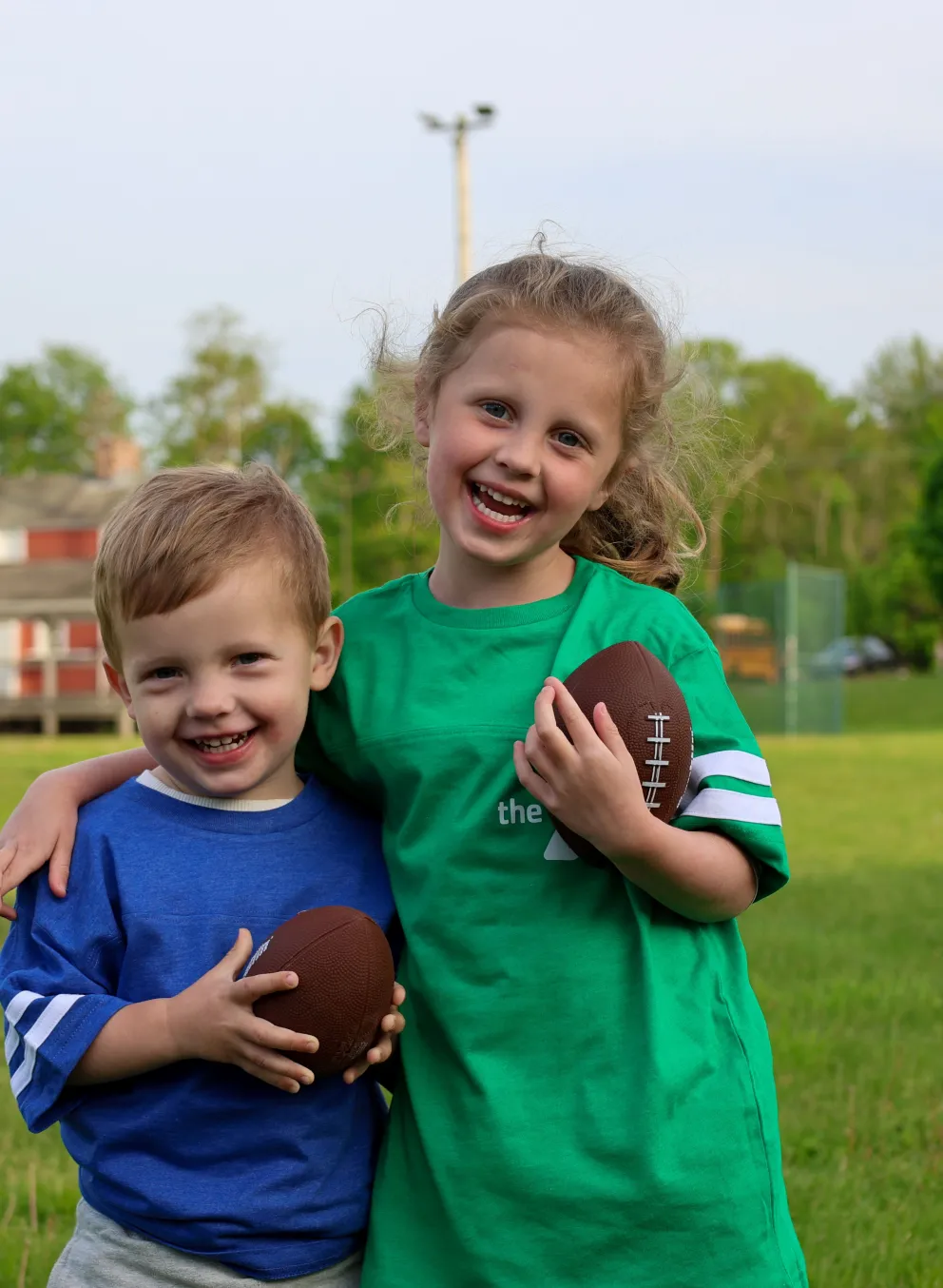 Boy and girl holding footballs