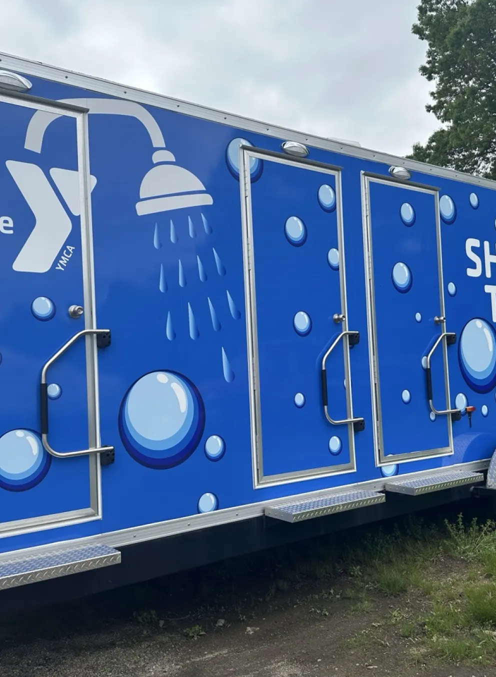 Blue trailer that says "Shower on the Move" with bubbles.
