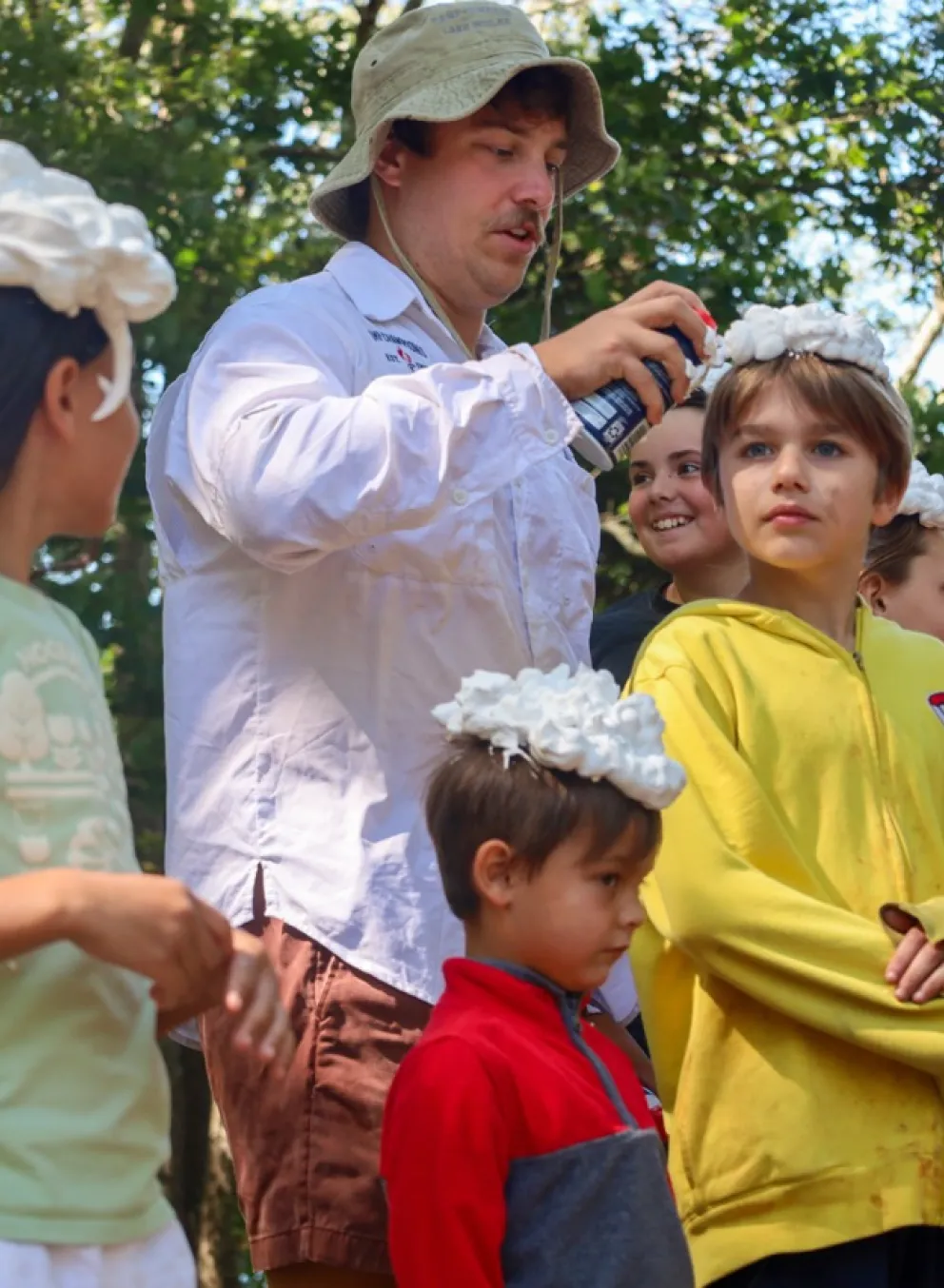 Line of campers having shaving cream put on their hair by a counselor