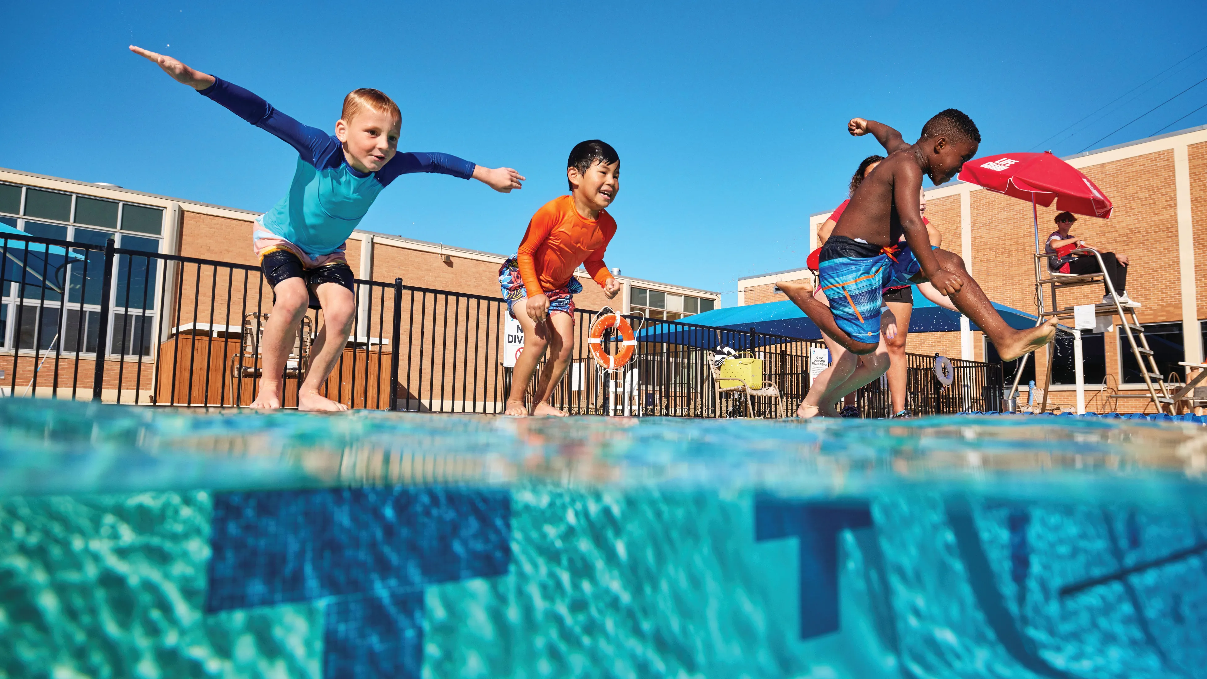 Kids jumping into an outdoor pool