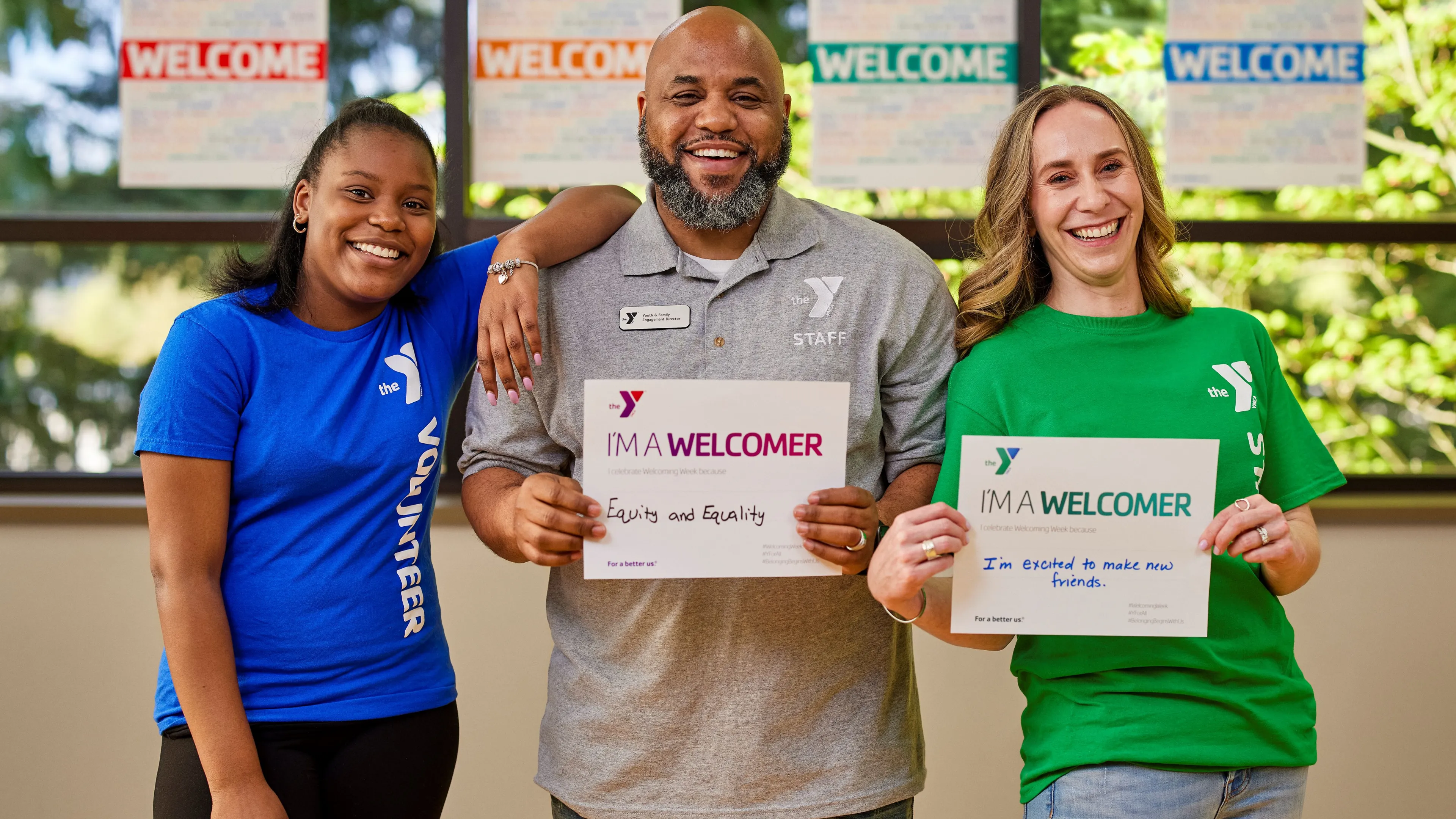 2 female and 1 male staff holding "I'm a welcomer" signs