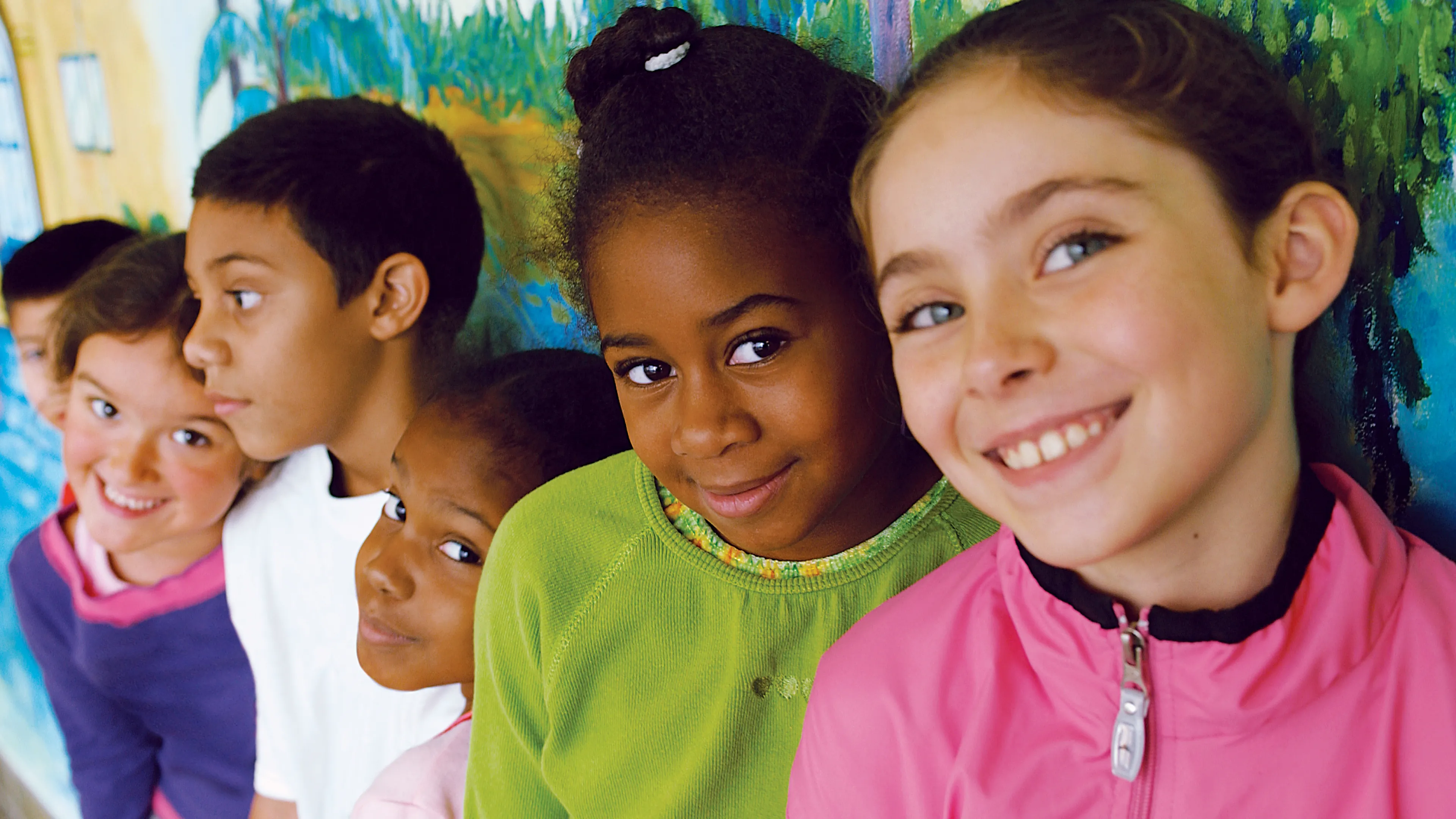 Boys and girls lined up against a wall smiling