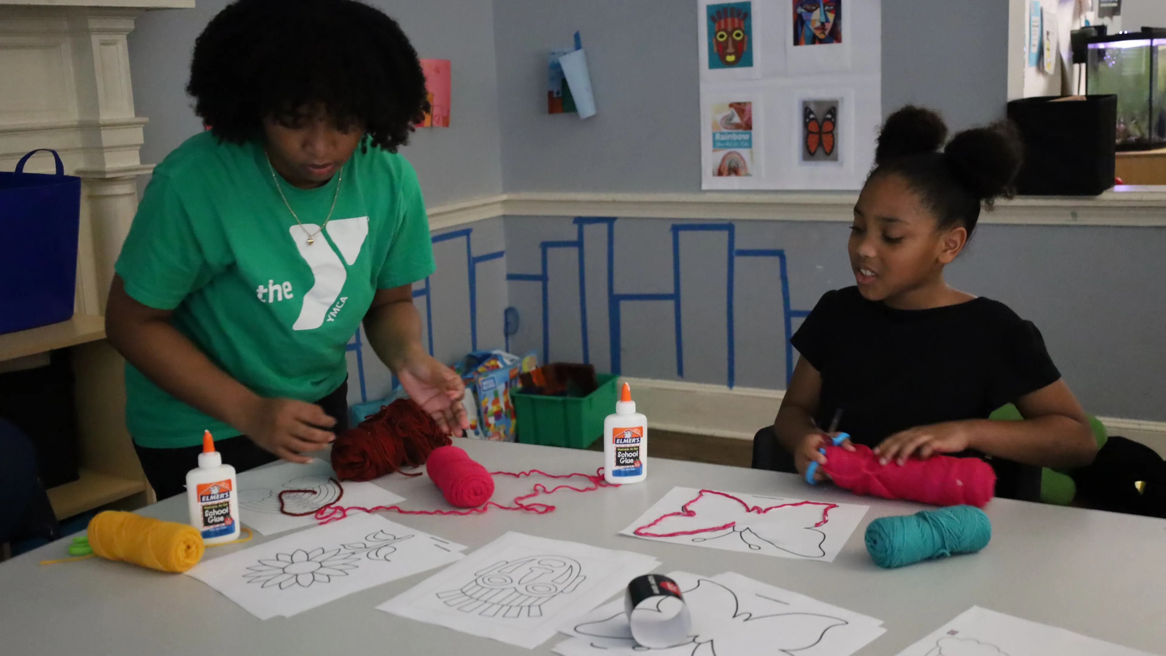 Female staff assisting a girl with her art project