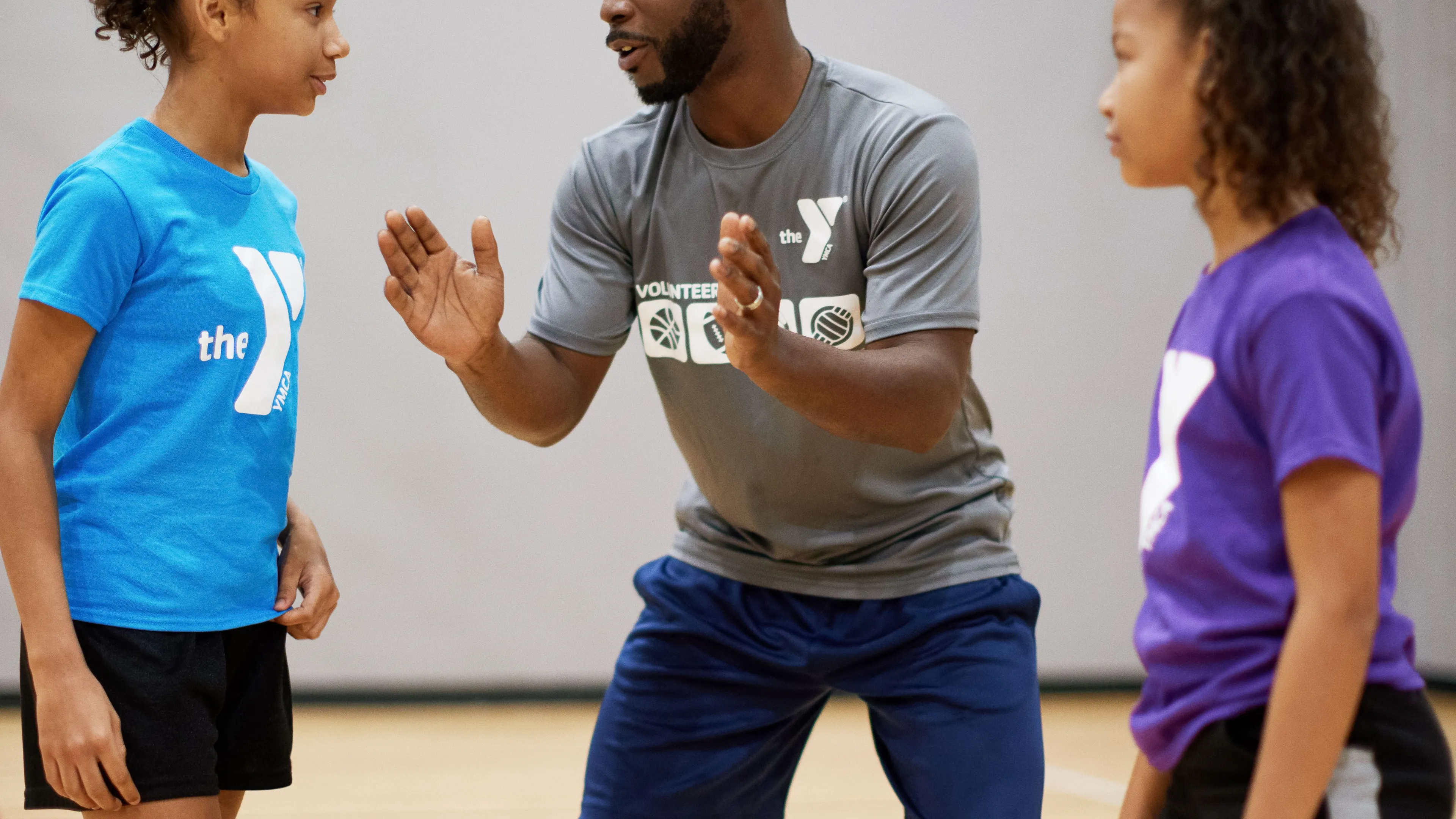 Male sports coach coaching to two female teenagers