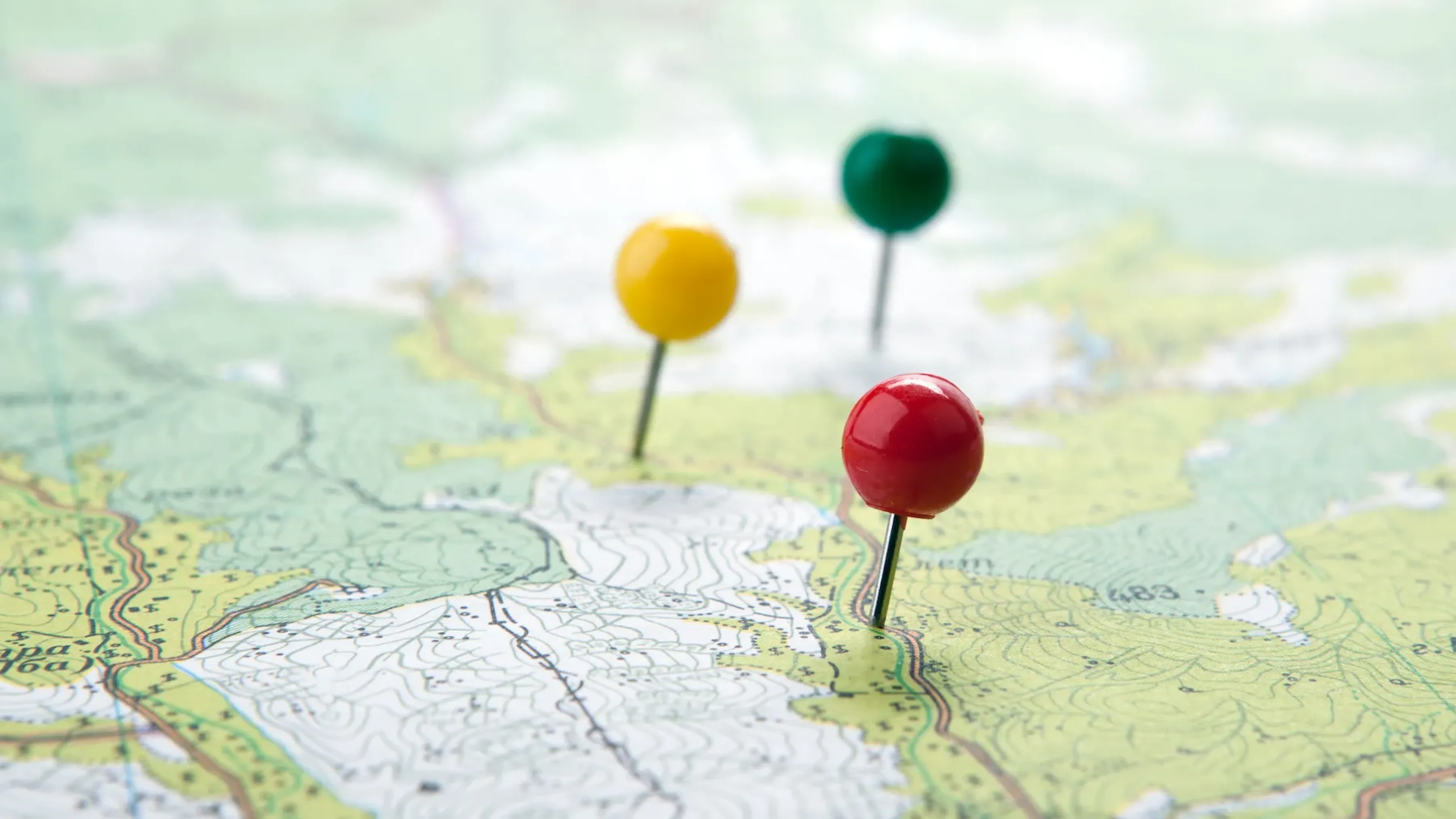 Map with a red, a yellow, and a green pin.