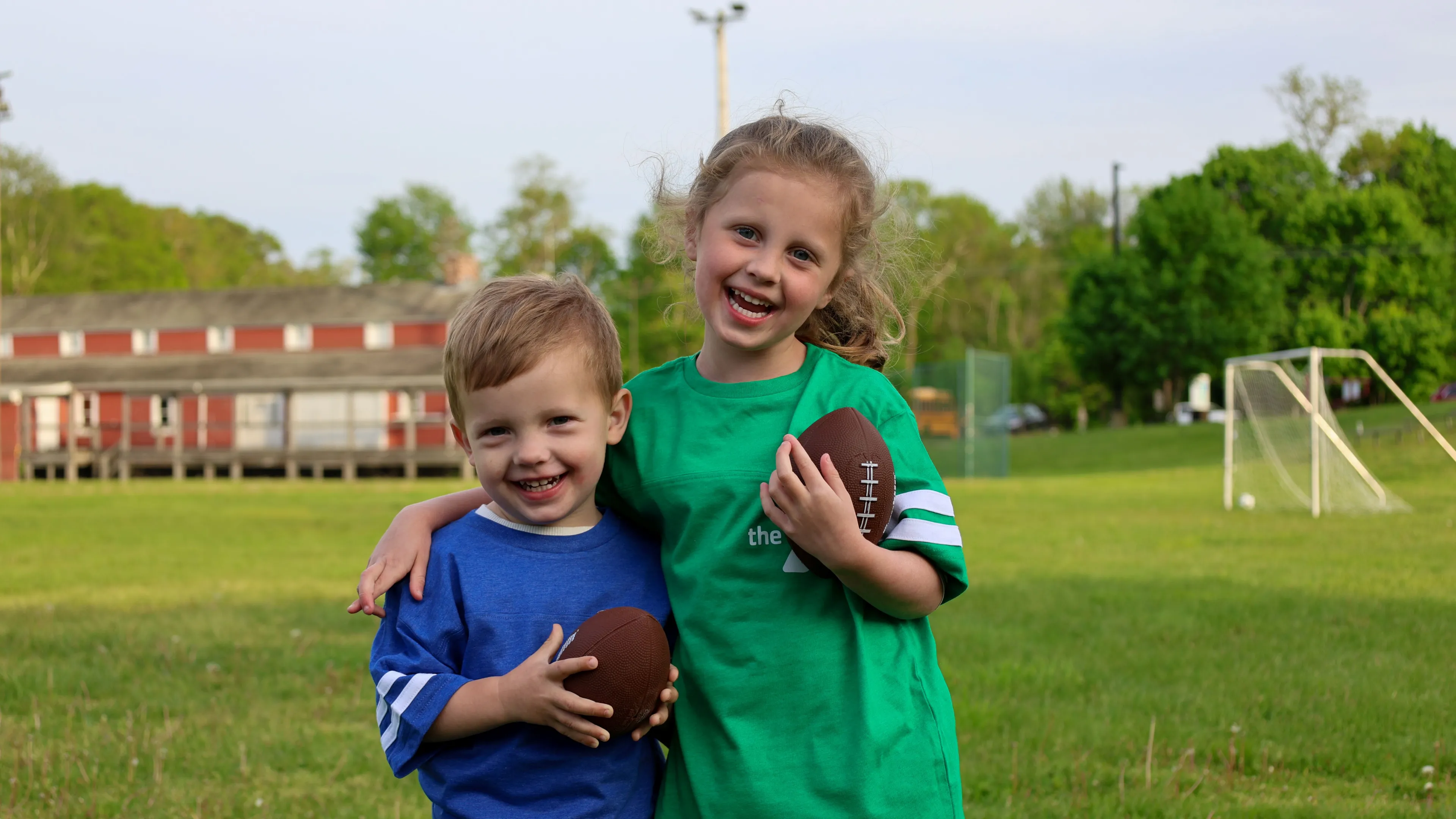 Boy and girl holding footballs