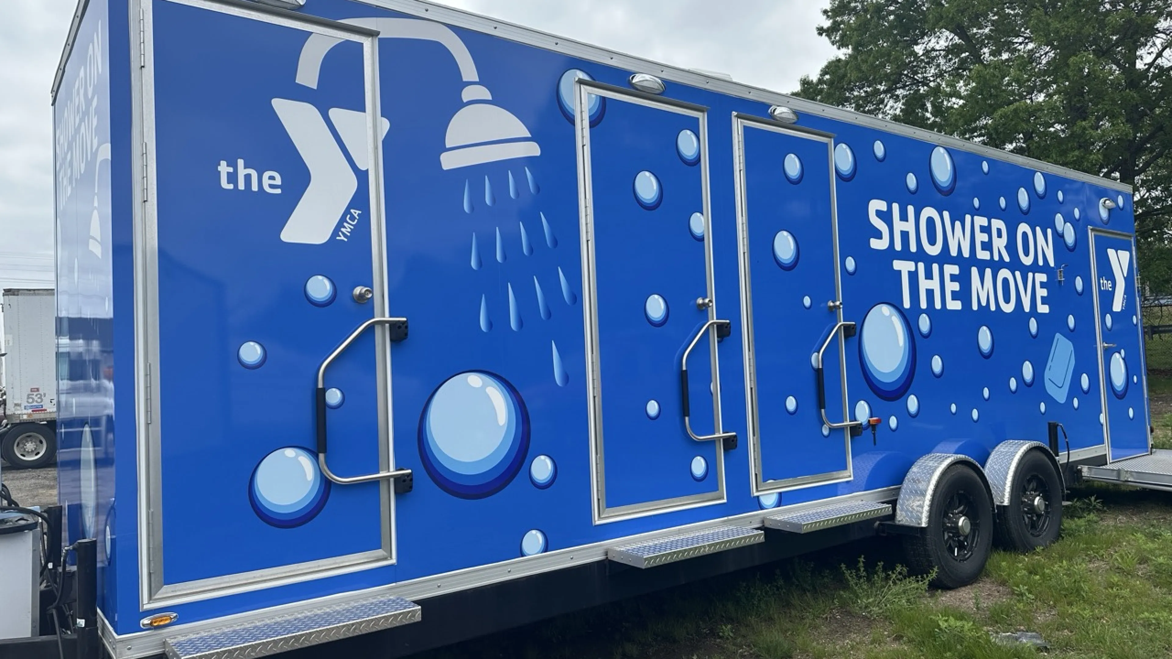 Blue trailer that says "Shower on the Move" with bubbles.