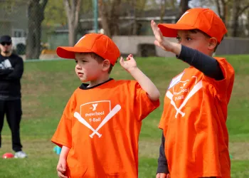 Two boys in orange t-ball shirts waving