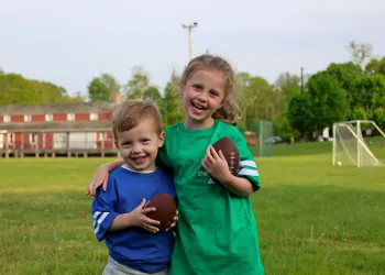 Boy and girl holding footballs
