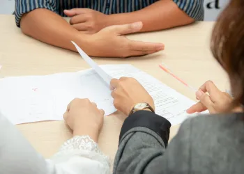 Three people sitting at a table with papers.