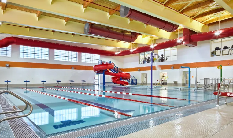 MacColl YMCA's Indoor Pool with 6 - 25-yard lap lanes, an Activity Pool, a splash pad, and a double-loop waterslide.