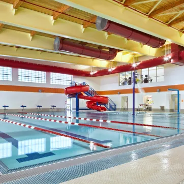MacColl YMCA's Indoor Pool with 6 - 25-yard lap lanes, an Activity Pool, a splash pad, and a double-loop waterslide.
