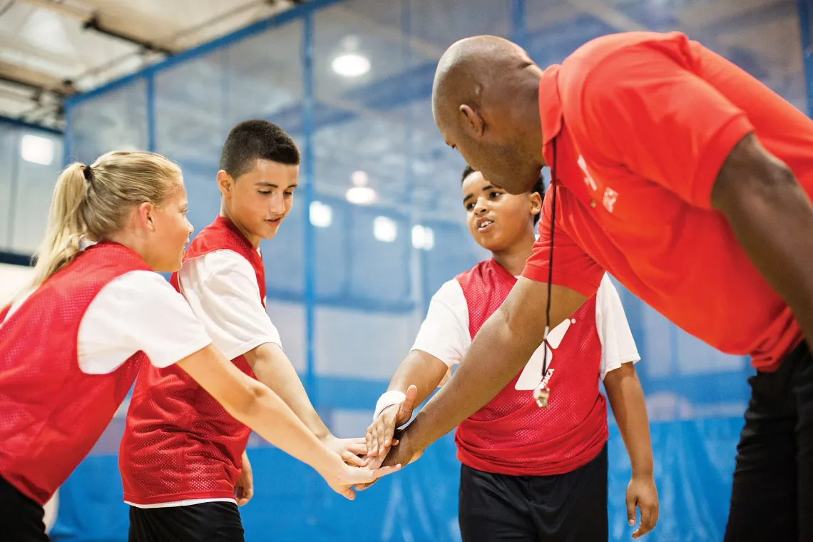 Coach with three basketball players surrounding him