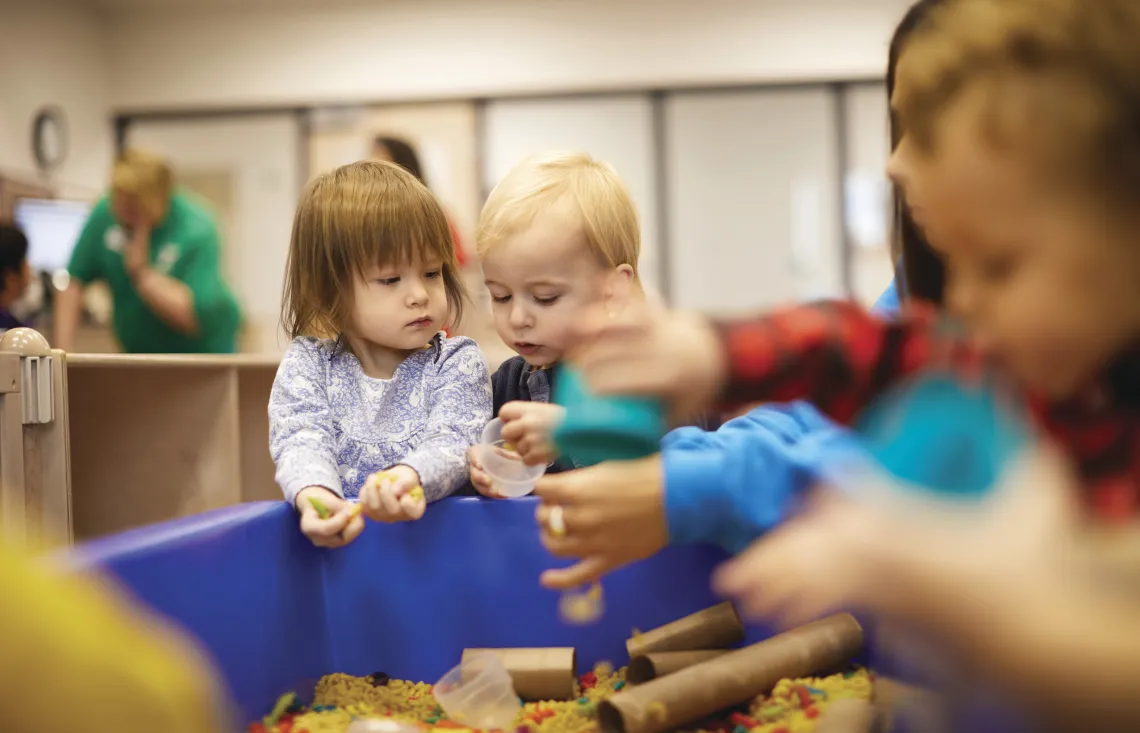 Toddlers playing in toy bin