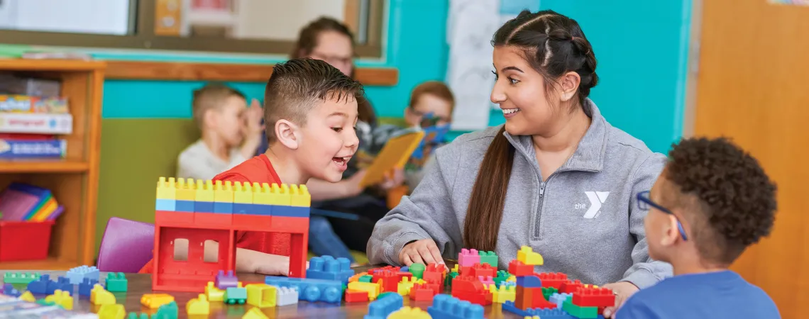Female staff sitting with two boys playing with legos