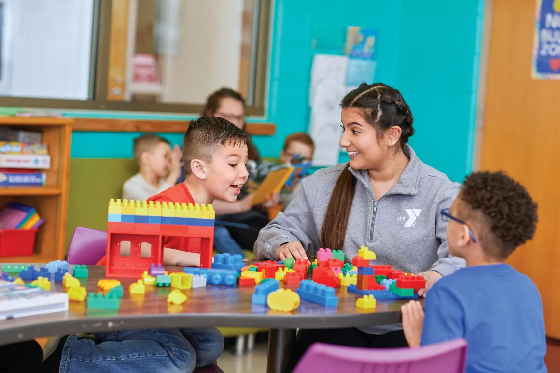 Female staff sitting with two boys playing with legos