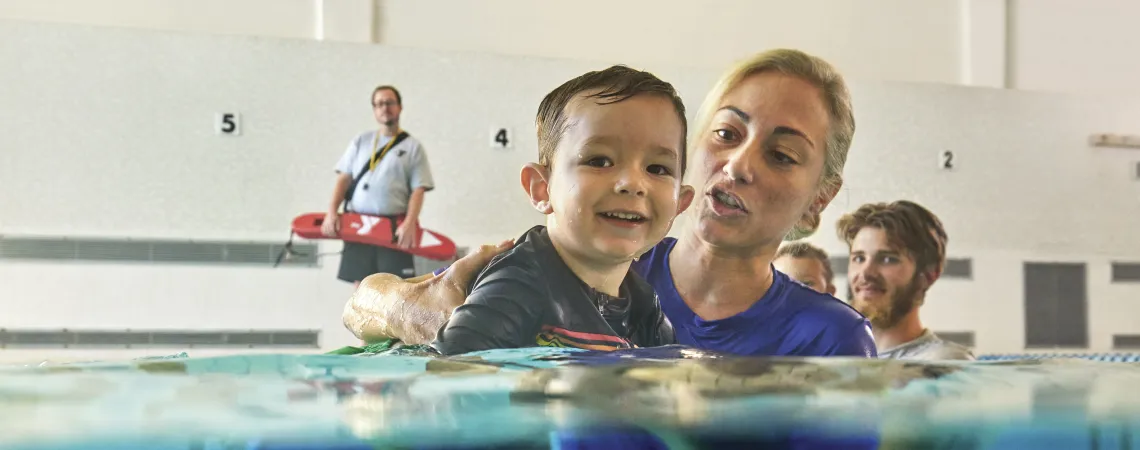 Female swim instructor teaching a young boy to siwm