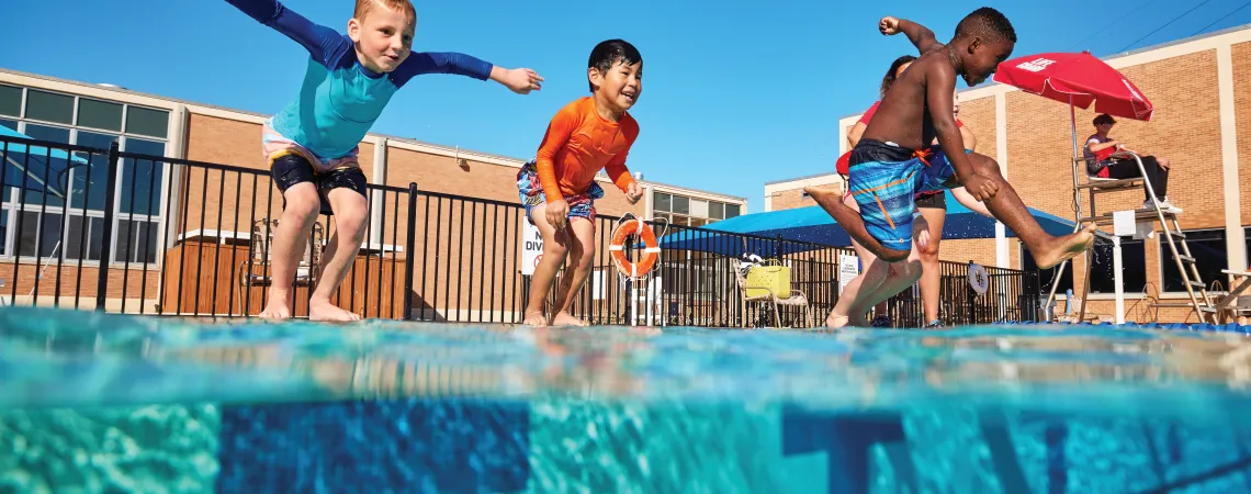 Kids jumping into an outdoor pool