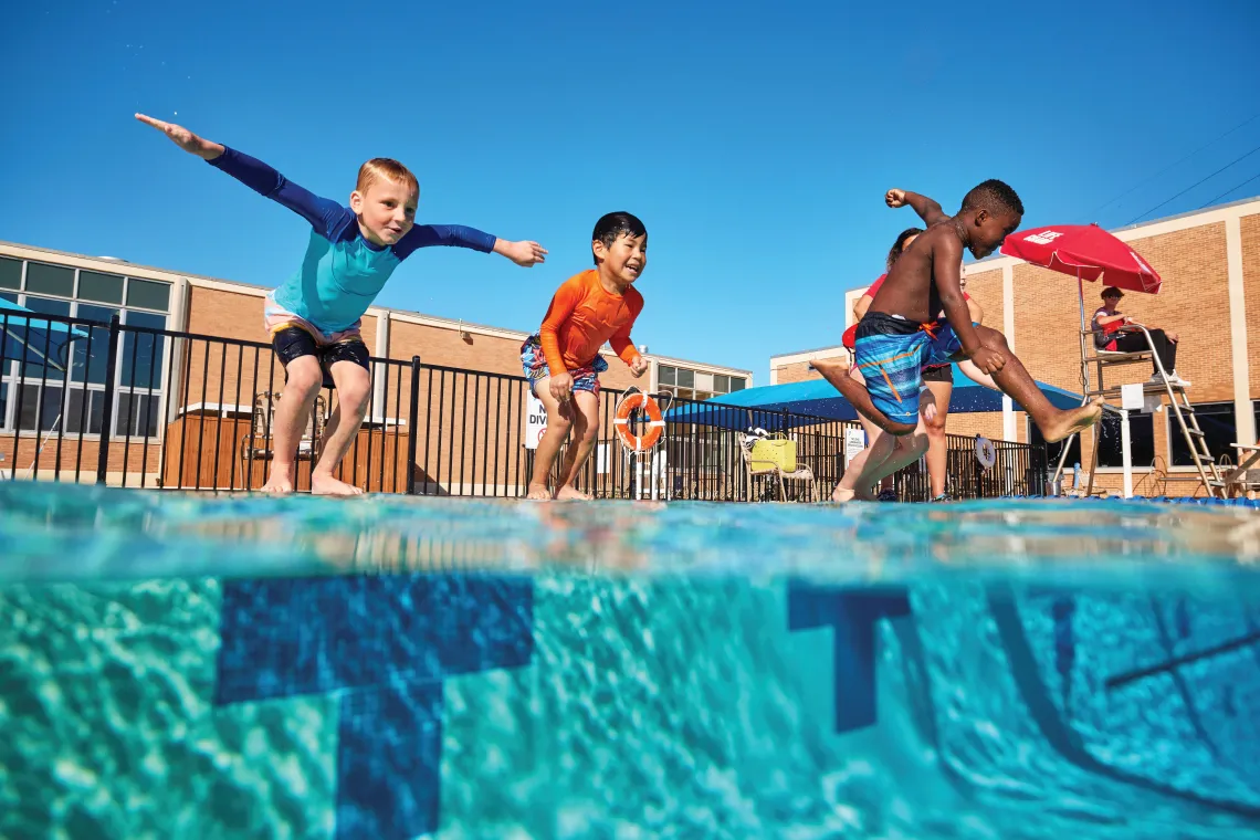 Kids jumping into an outdoor pool