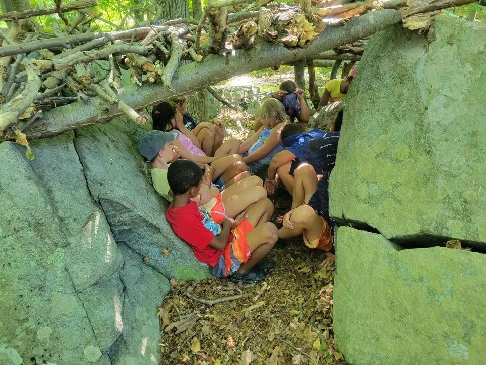 Campers sitting underneath the fort they made out of nature