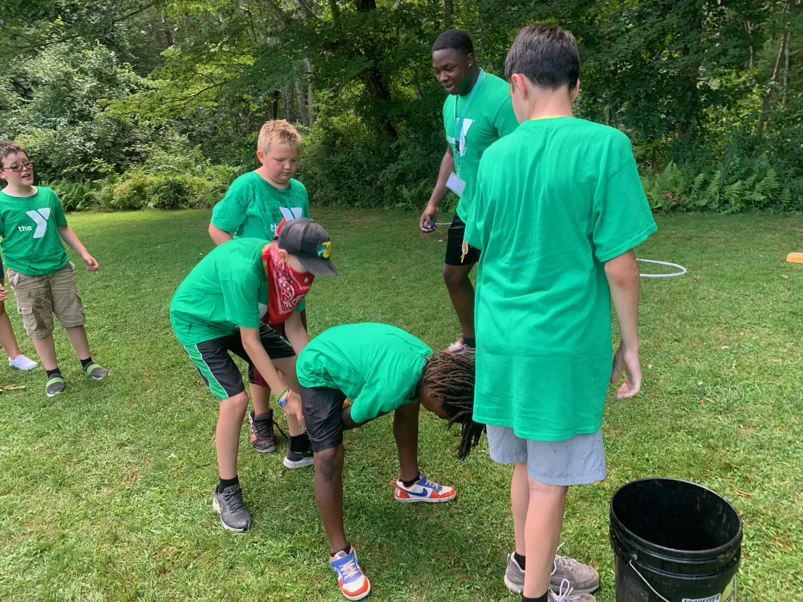 Boys participating in a relay race of passing an object underneath themselves