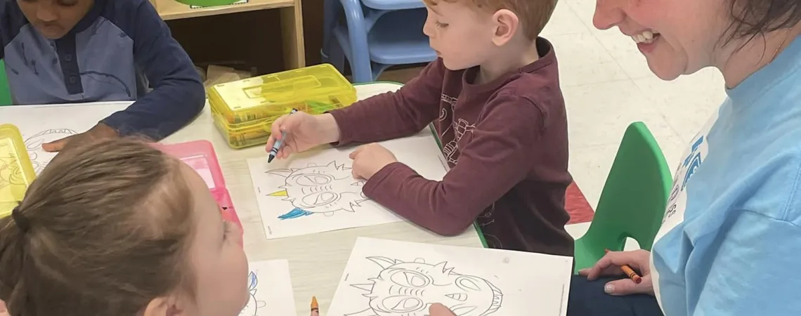 Teacher sitting at table with 3 young students