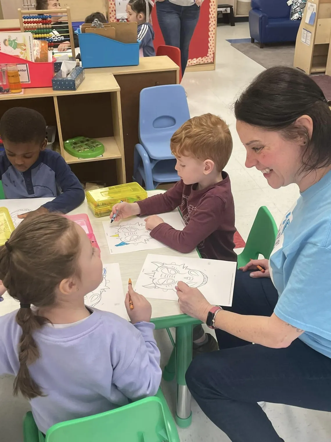 Teacher sitting at table with 3 young students