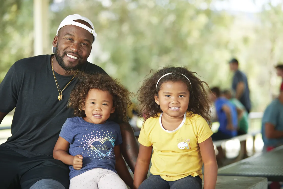 Dad sitting with two daughters