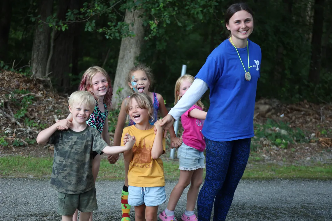 Female counselor standing with 5 campers