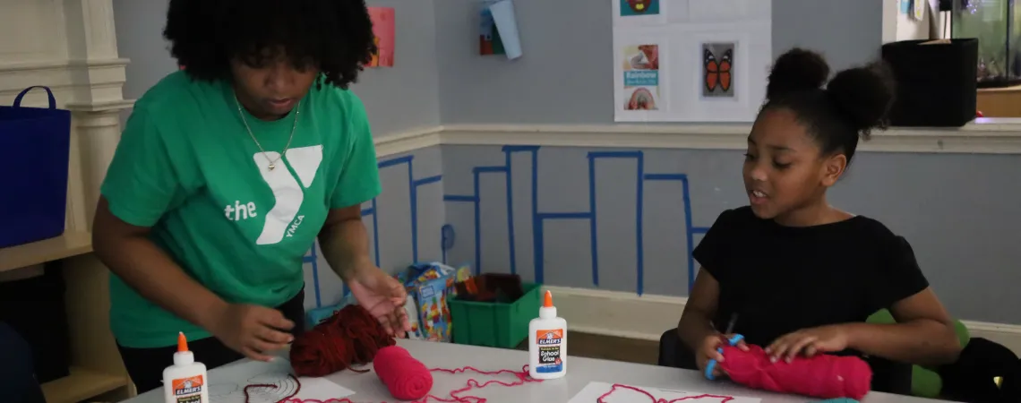 Female staff assisting a girl with her art project