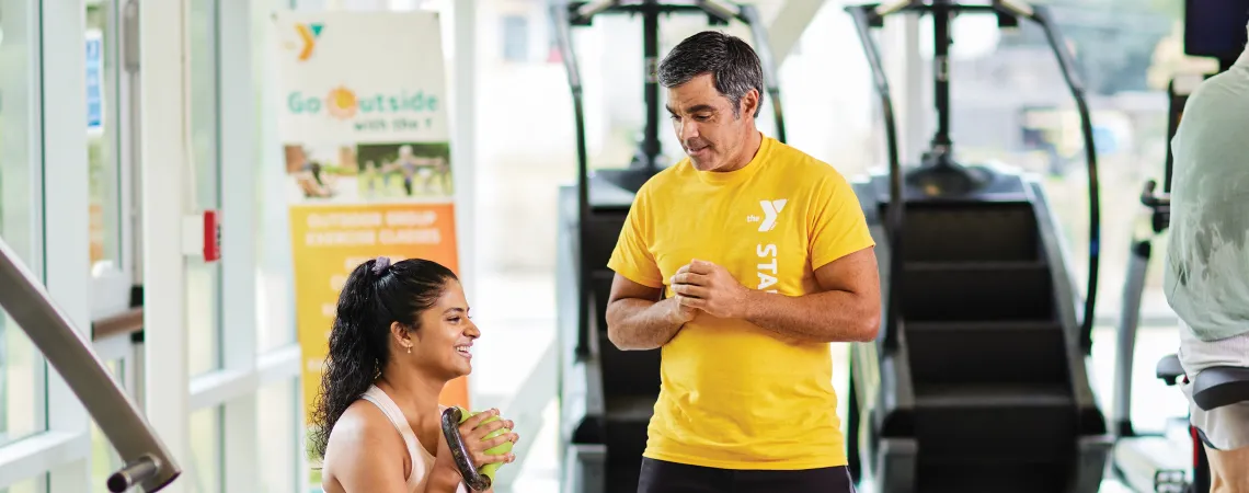 Trainer helping female squat with kettle bell