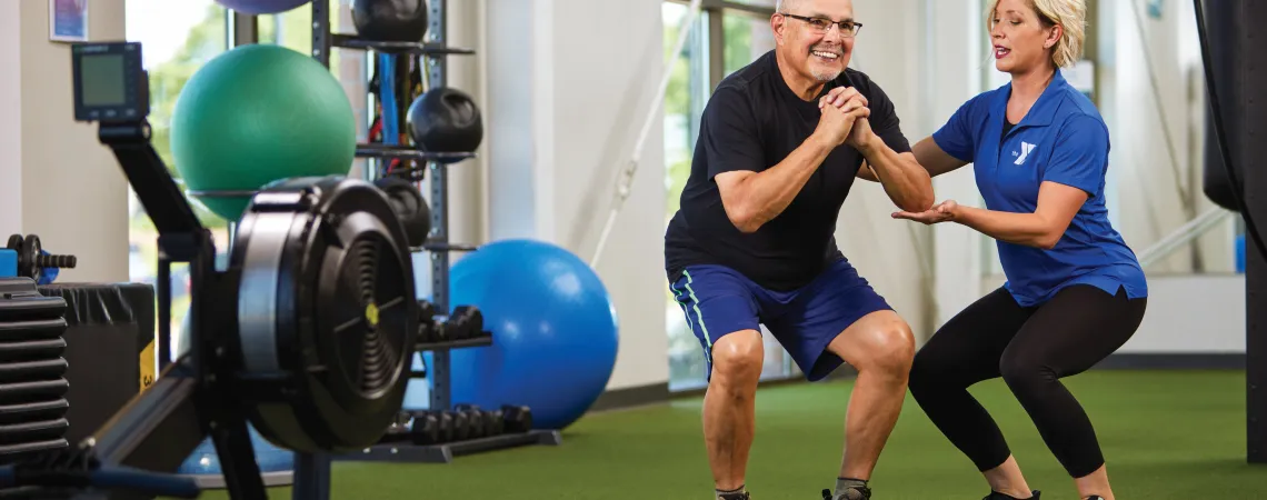 Trainer assisting man with squats