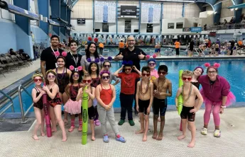 Swim Team posing with coaches at Swim Meet