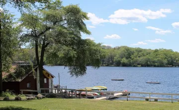 A waterfront view of Camp Westwood showcasing kayaks, paddle boards, and canoes.